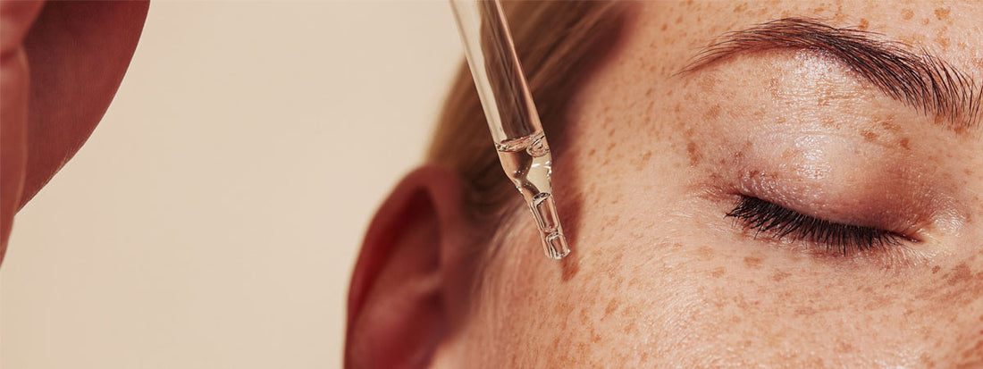 A close-up of a person applying serum to their face.