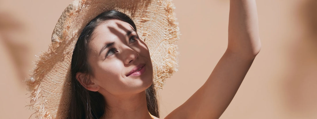 Woman with a straw hat, sunlight casting shadows on her face.